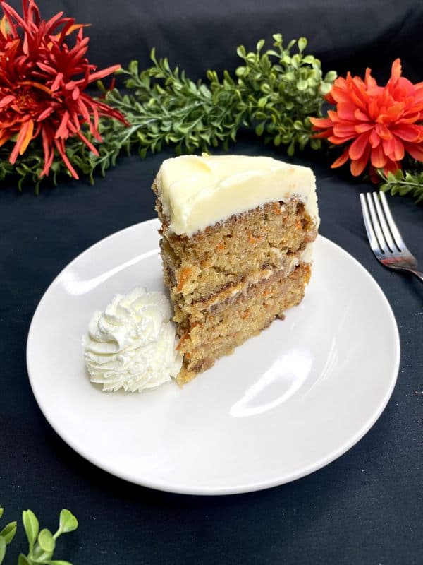 A slice of two-layer carrot cake with cream cheese frosting.