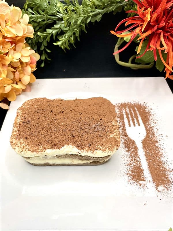 A portion of tiramisu dusted with cocoa.